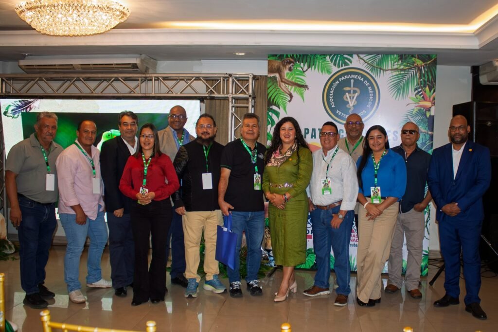 Grupo de participantes y representantes institucionales posa frente al escenario del Simposio