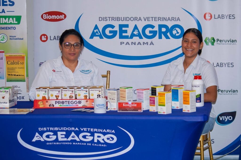Representantes de Distribuidora Veterinaria AGEAGRO Panamá en su stand durante el Simposio de Medicina Veterinaria APMV 2026, junto a productos veterinarios exhibidos. Títuloexhibidos