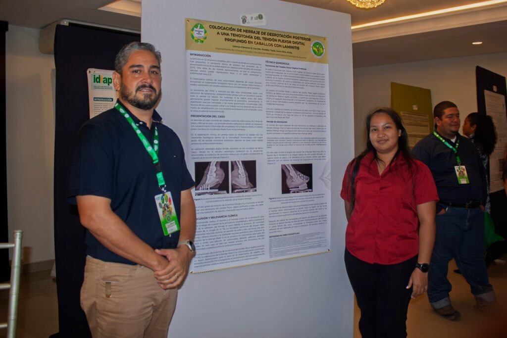 Presentador posa junto a un póster científico en el área académica